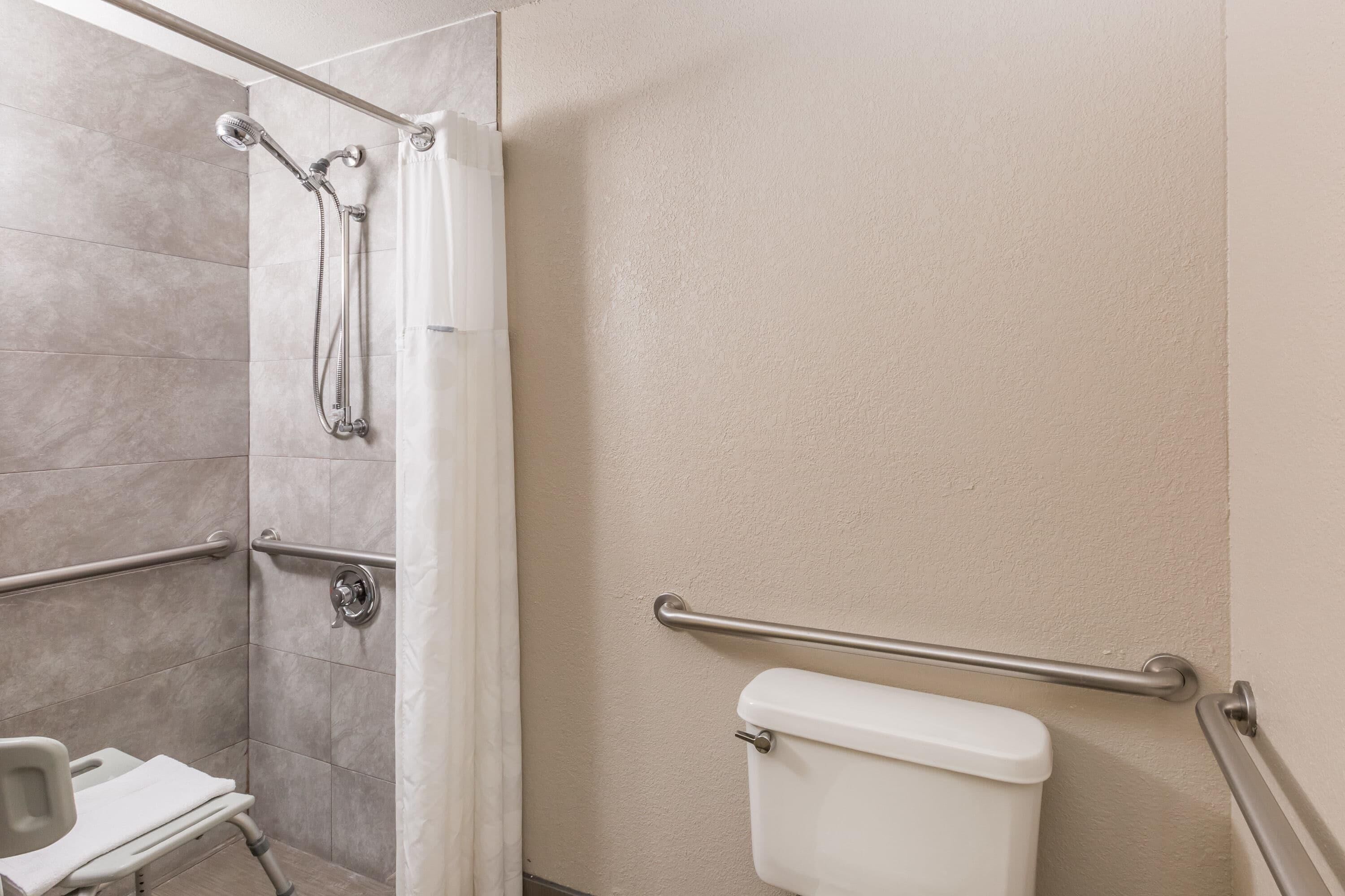Une salle de bain équipée d’une douche, de barres d’appui et de toilettes.