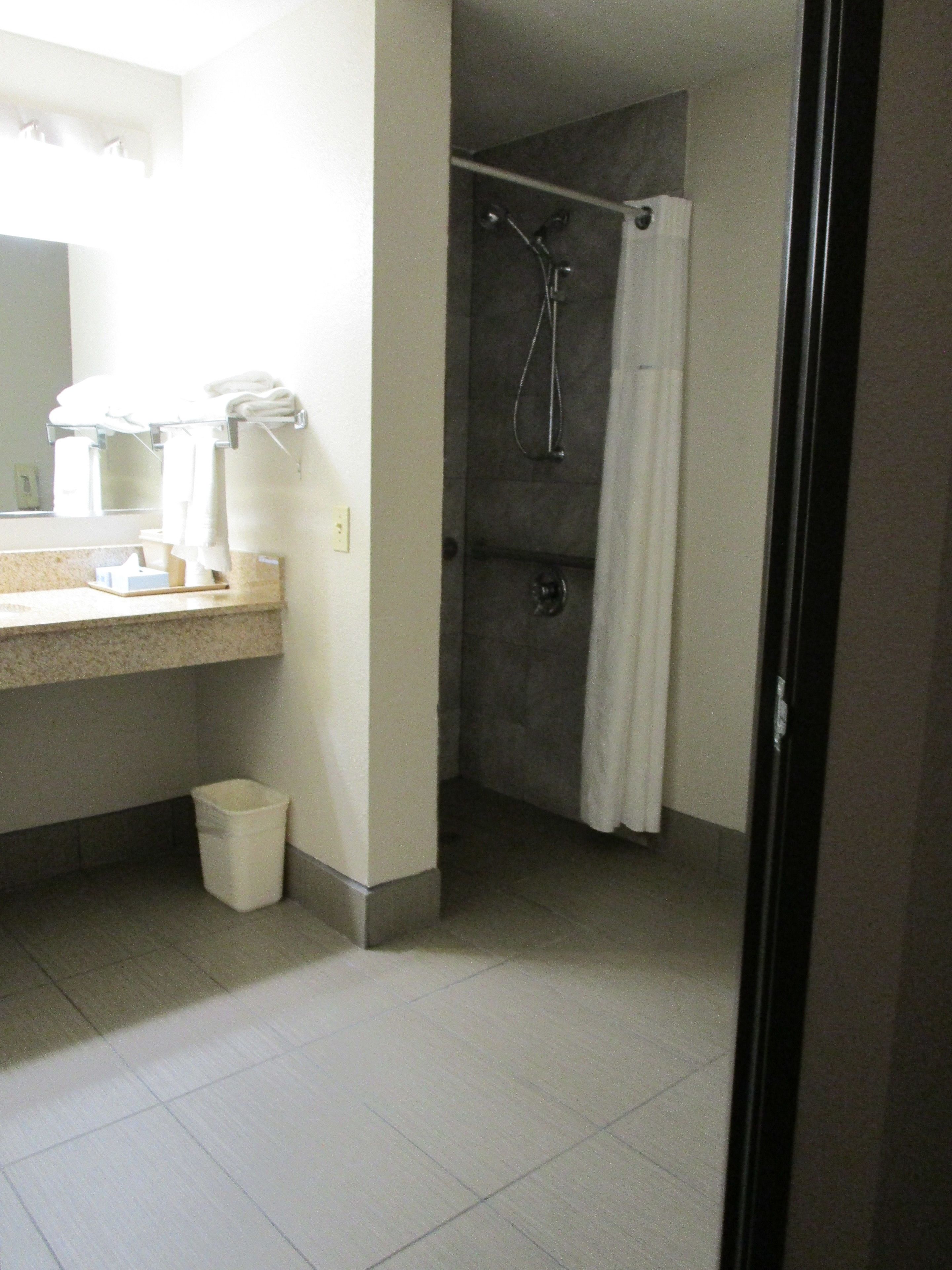 Un baño con ducha, lavamanos y espejo.