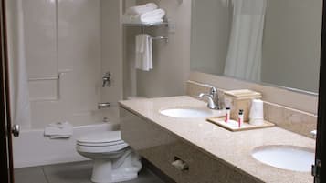 Un baño con bañera, dos lavamanos, inodoro y espejo.