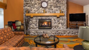 A living room with a stone fireplace, a television, and a sofa.