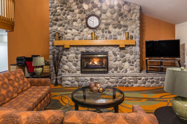 Una sala de estar con chimenea de piedra, televisor y sofá.
