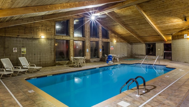 An indoor swimming pool with wooden beams, tiled walls, and lounge chairs.