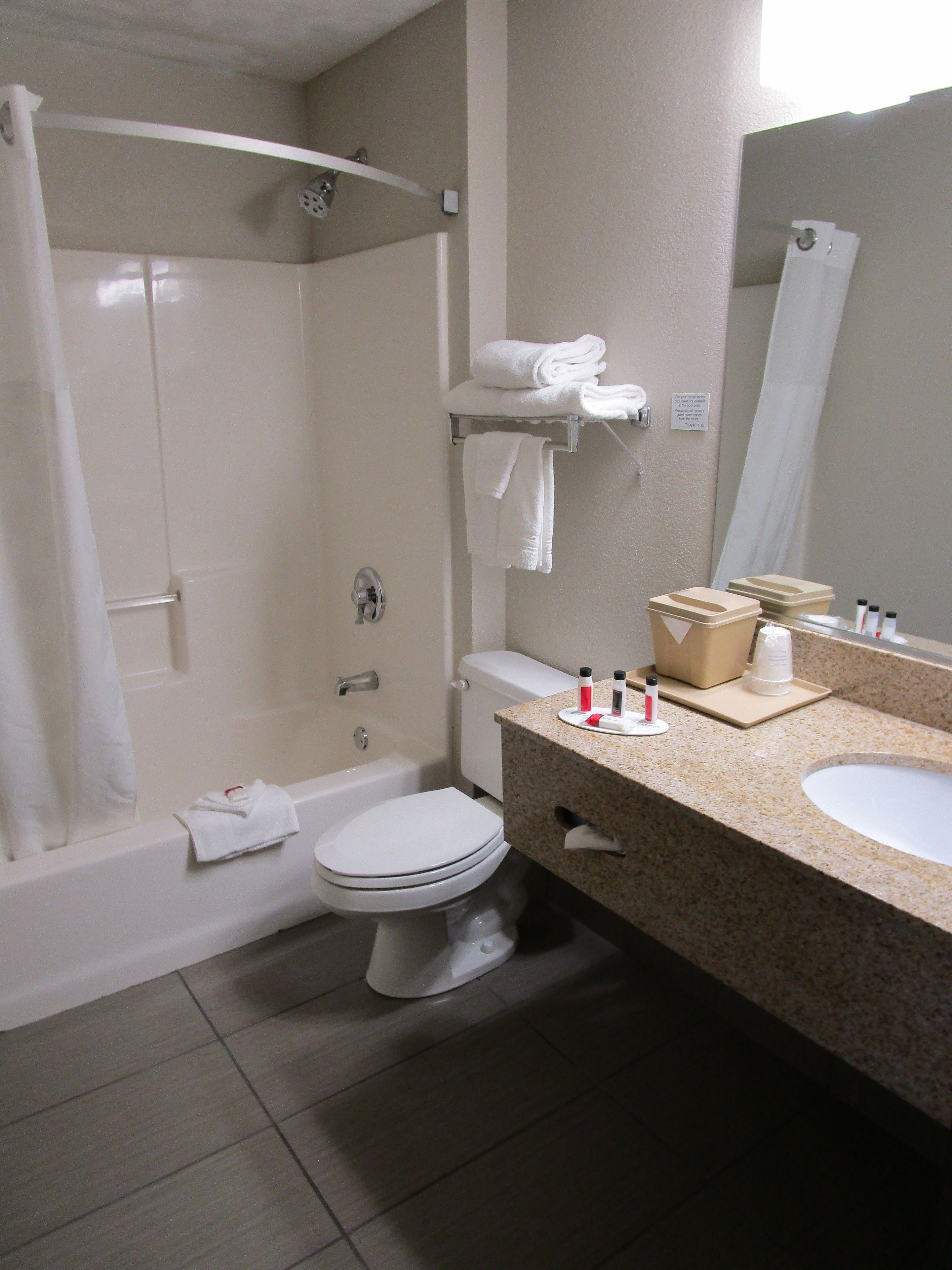 A bathroom with a bathtub, toilet, and sink. There are towels on the wall and a mirror above the sink.