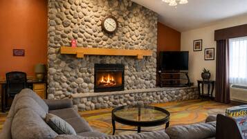 A living room with a stone fireplace, a television, and a sofa.