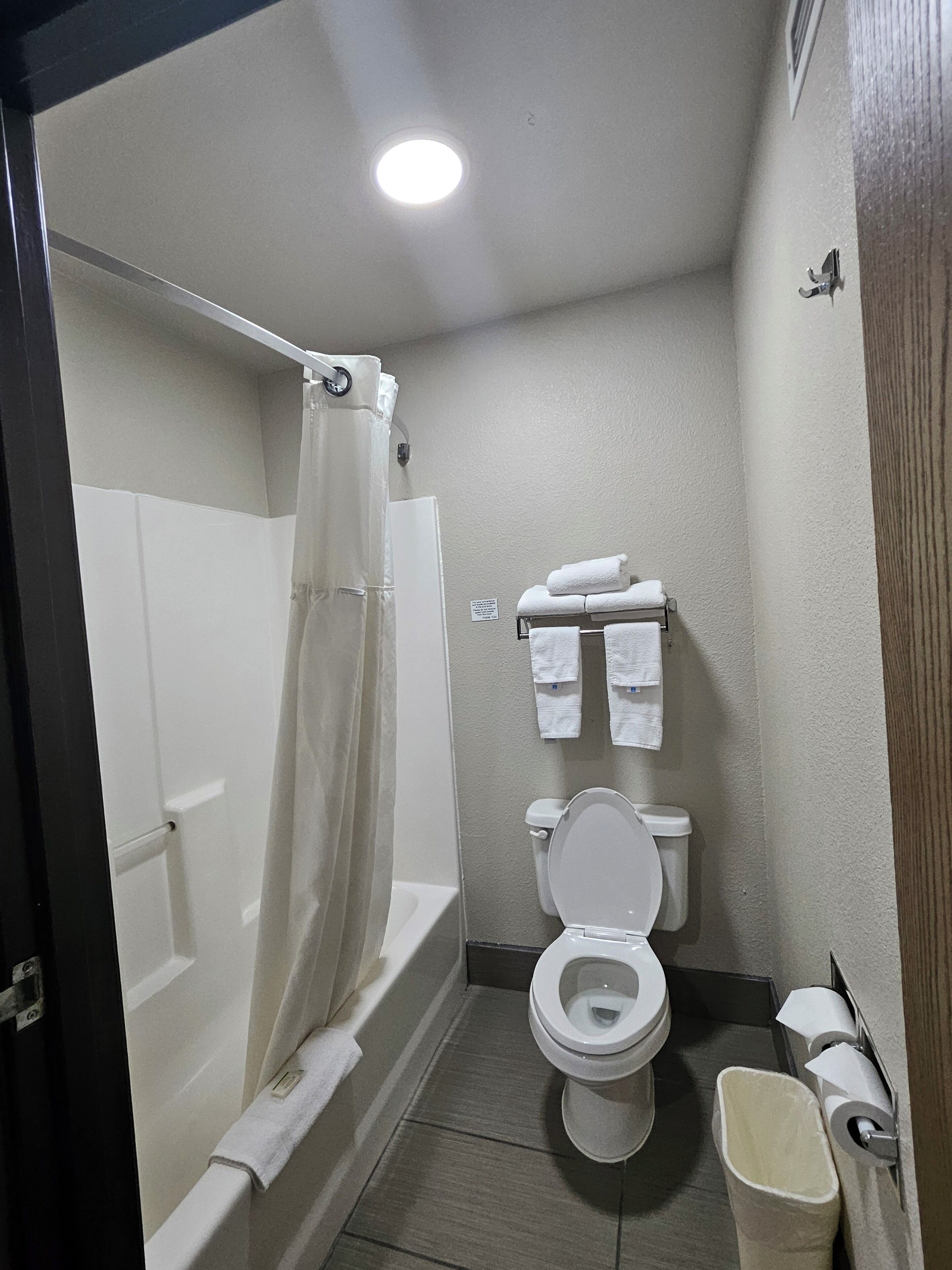 A small bathroom with a shower, toilet, and a towel rack.