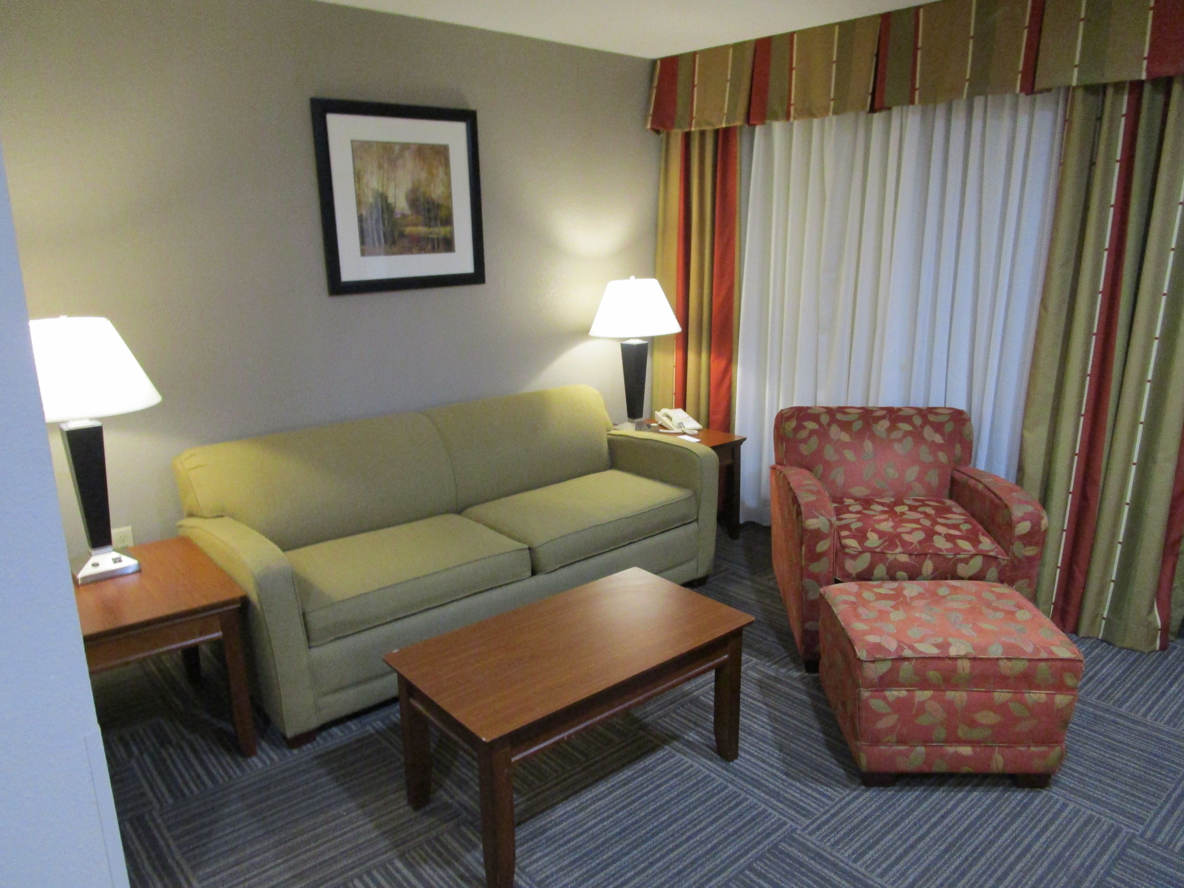 Ein Hotelzimmer mit einer Couch, einem Sessel, einem kleinen Tisch und einer Lampe.