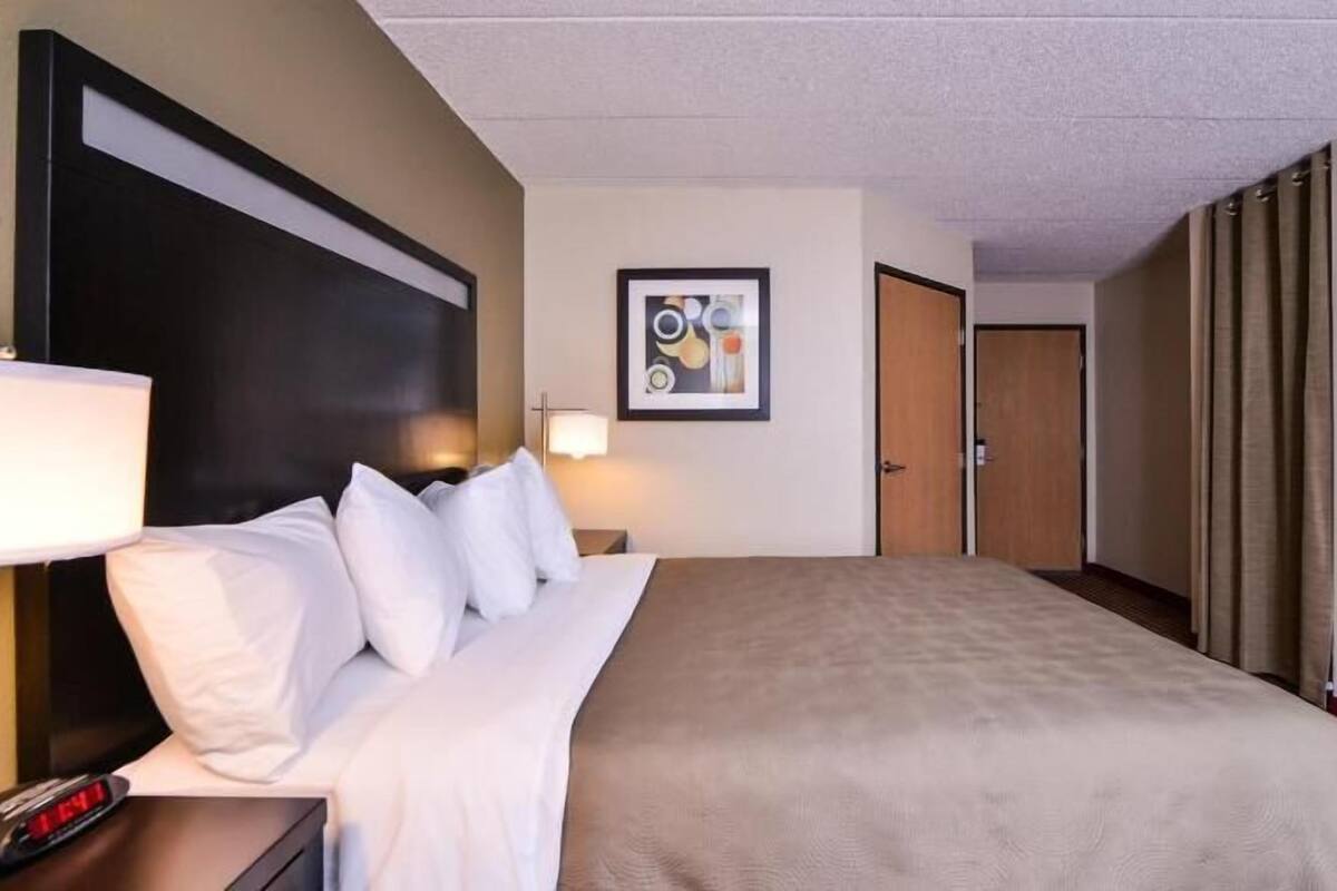 A hotel room with a bed, bedside tables, a lamp, a framed picture on the wall, and a door.