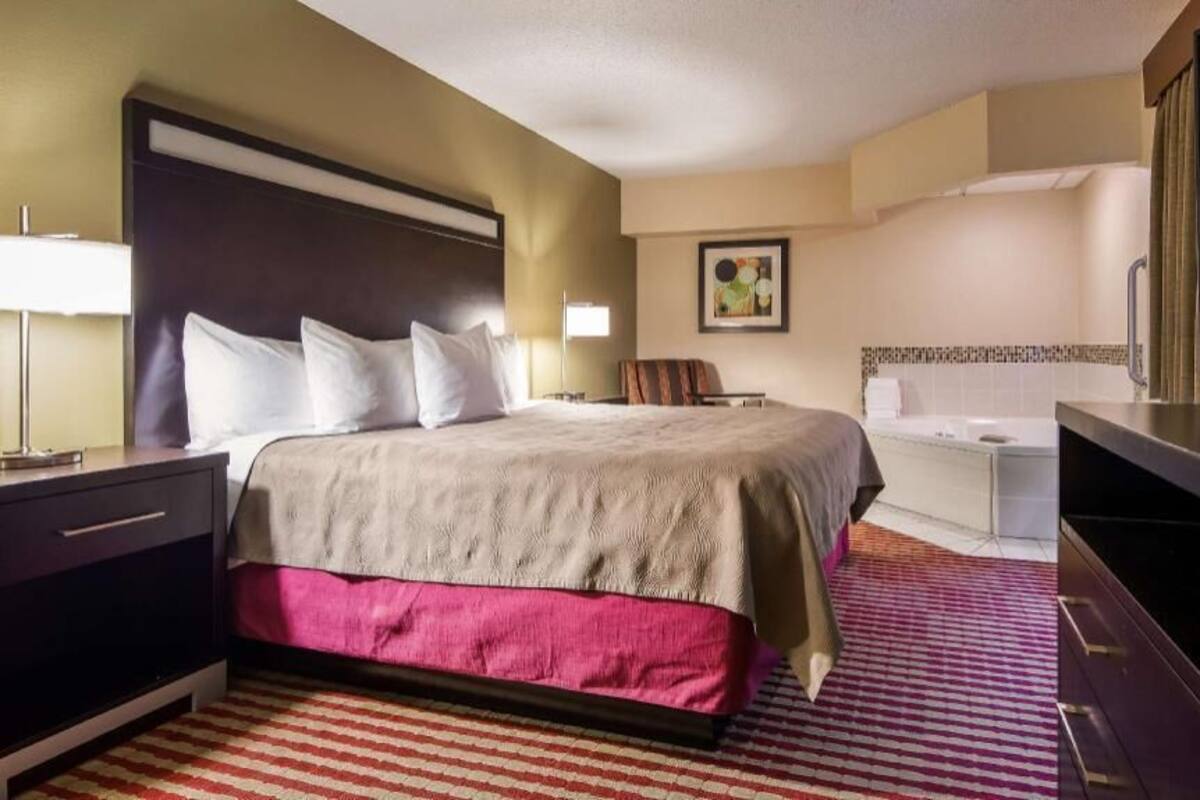A hotel room with a bed, a TV, a desk, and a bathroom.