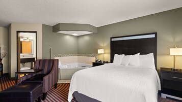 A hotel room with a large bed, a sitting area with a chair and table, a bathtub, and a desk with a lamp.