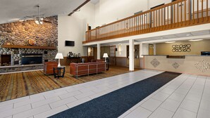 A spacious lobby with a stone wall, a fireplace, a reception desk, and a seating area. - Best Western Germantown Inn (Village of Germantown)