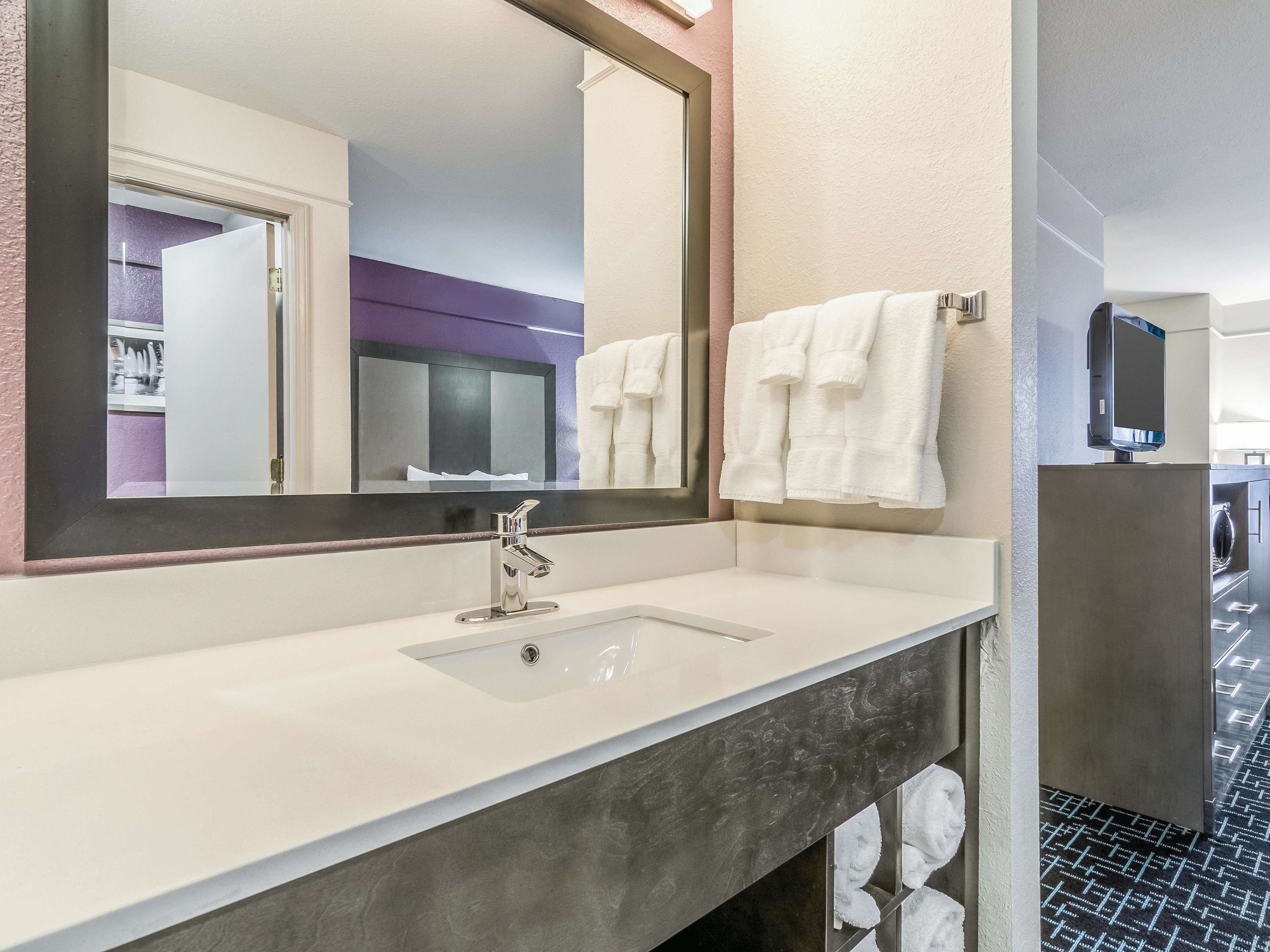 A modern bathroom with a large mirror, a sink, and a towel rack.