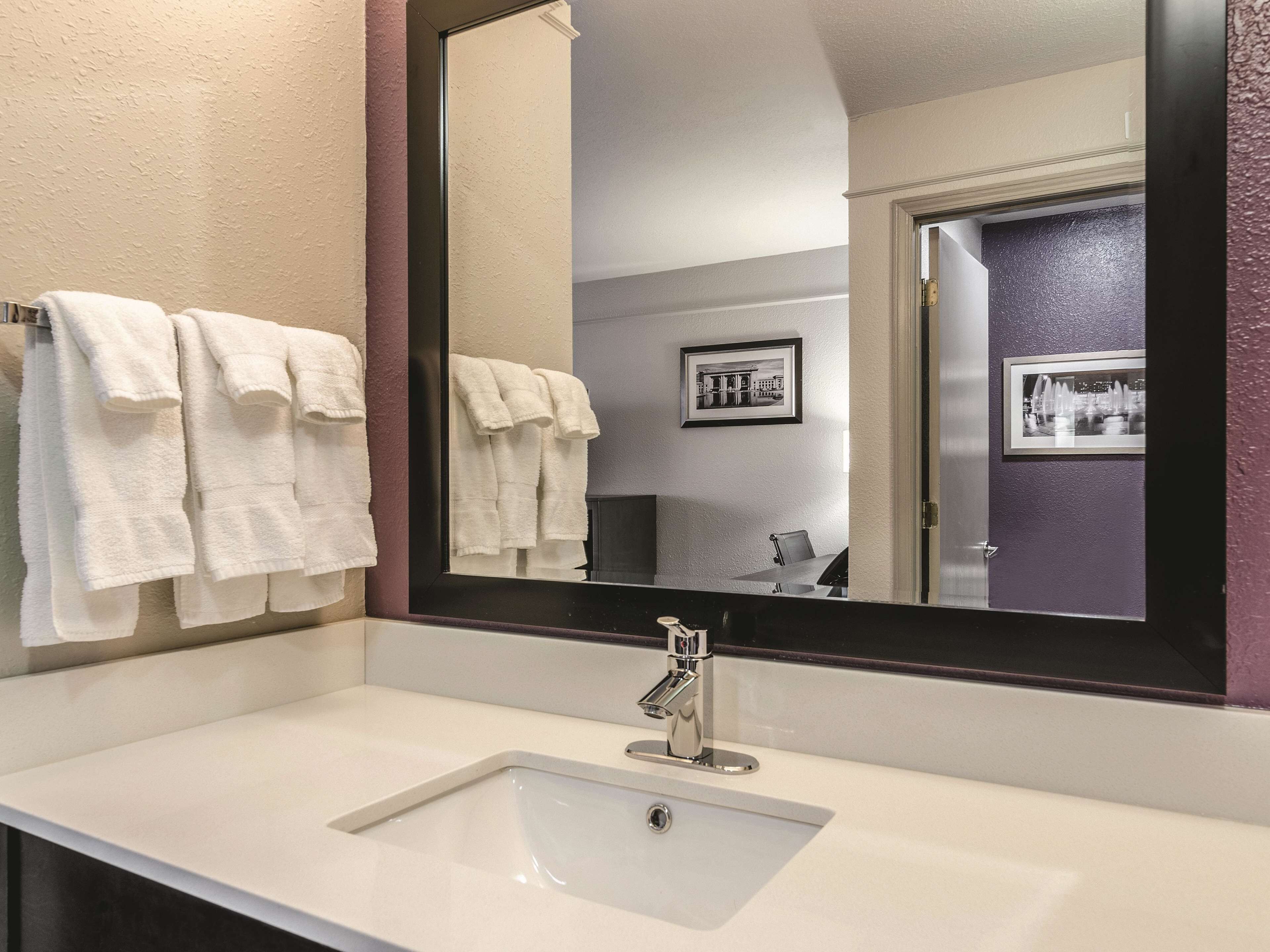 A bathroom with a white sink, a mirror, and two framed pictures on the wall.