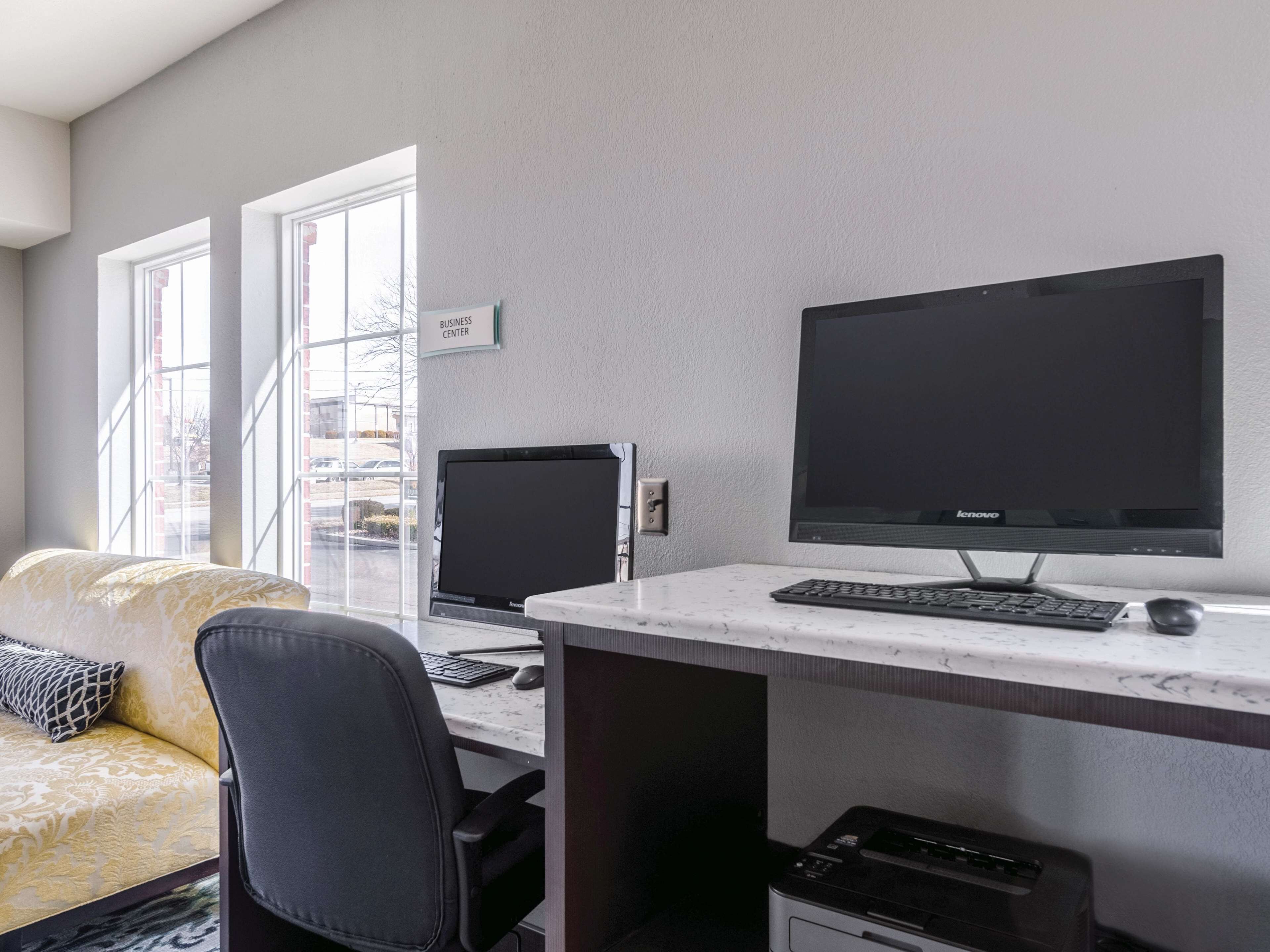 A workspace with two monitors, a keyboard, and a printer.