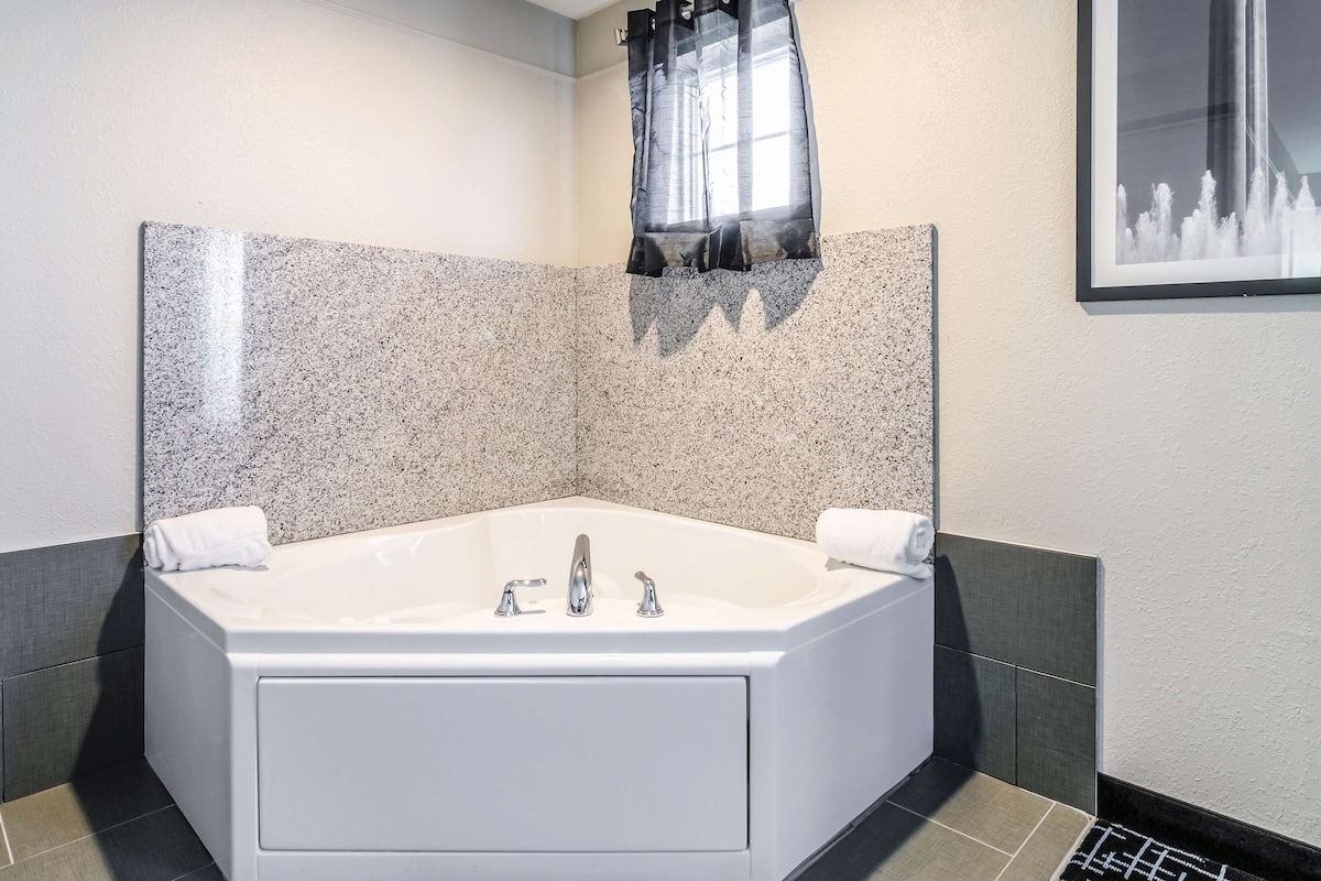 A modern bathroom with a freestanding bathtub, a shower area, and a large window with curtains.