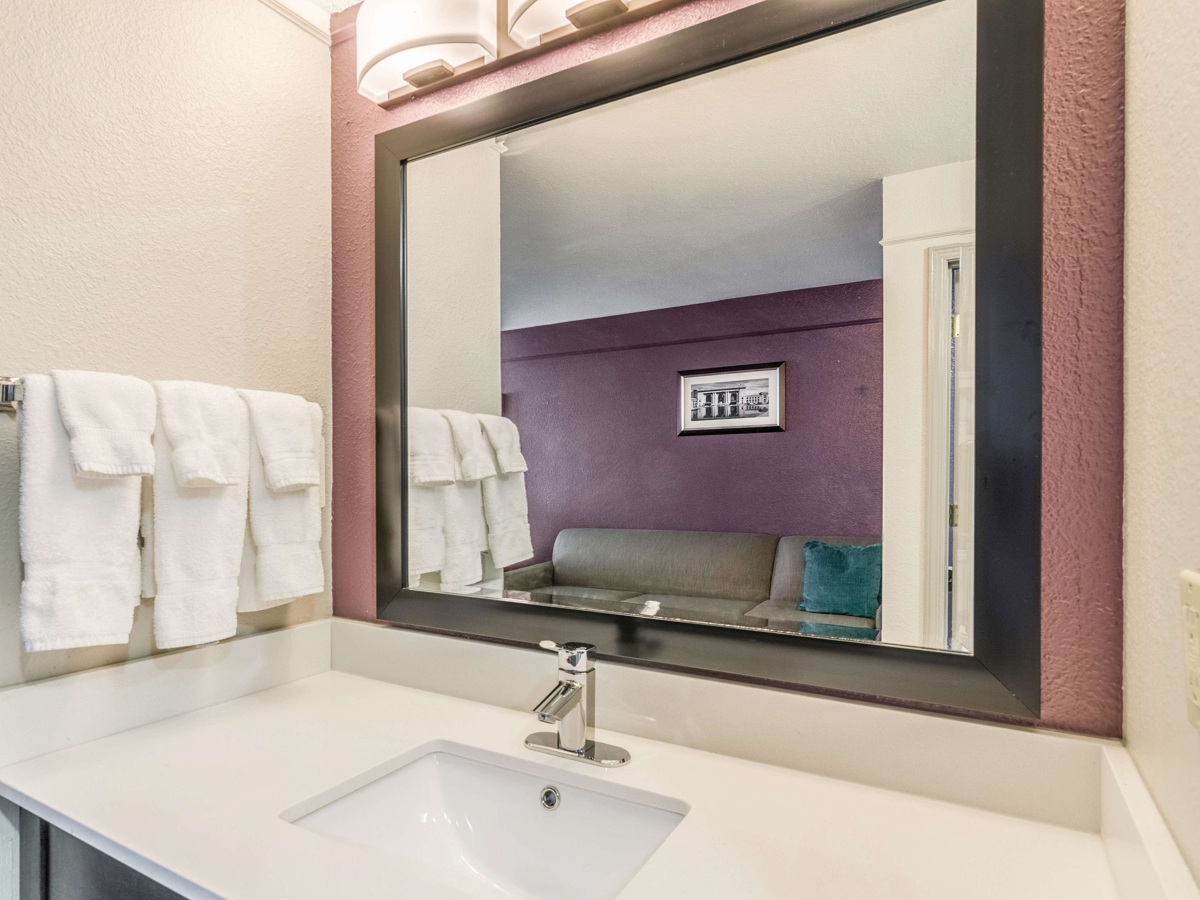 A bathroom with a white sink, a large mirror, and a purple wall.