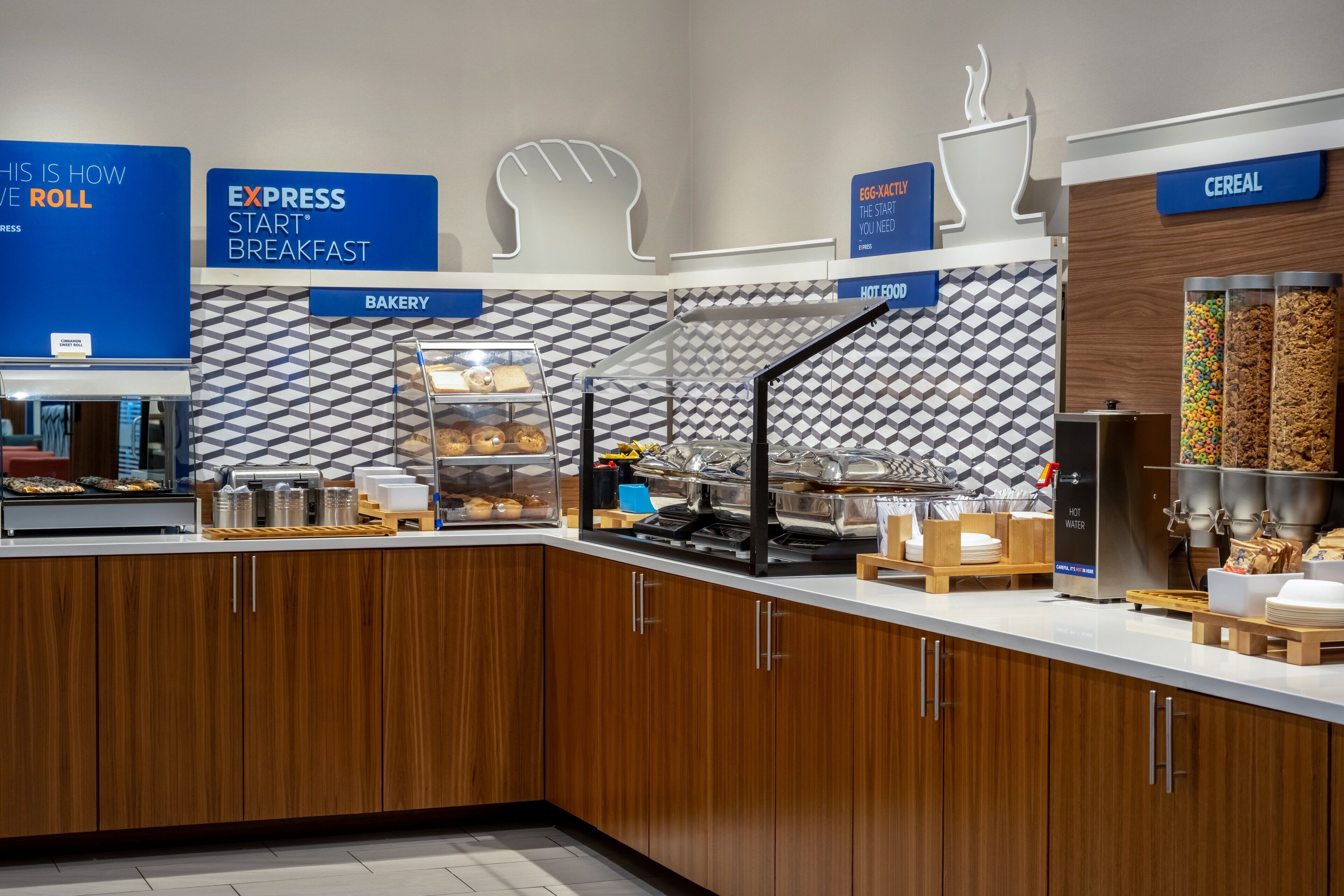 A modern breakfast area with labeled sections for roll, express breakfast, bakery, hot food, and cereal.