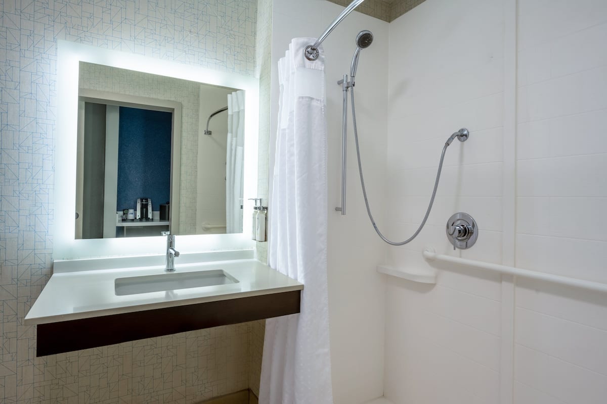 A bathroom with a white sink, mirror, and shower with a curtain.