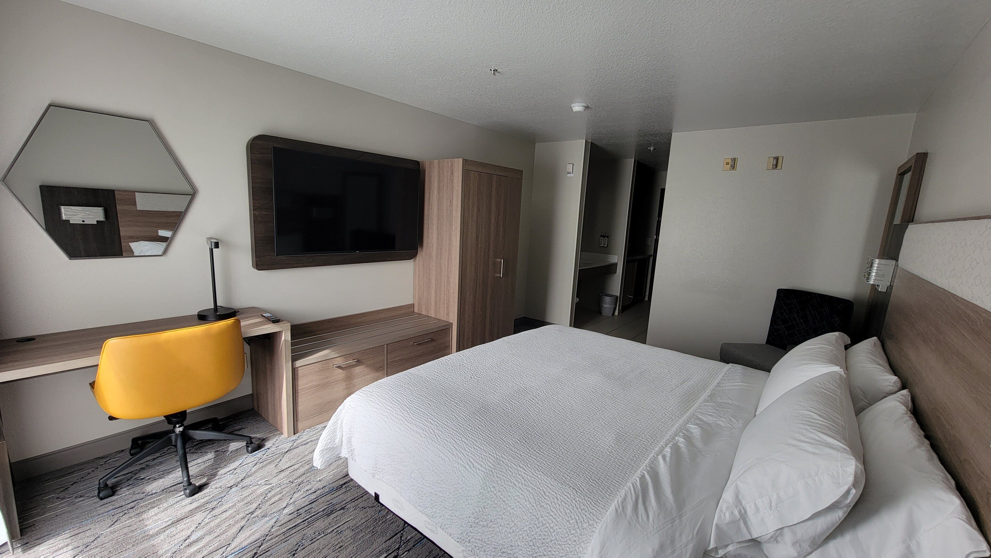 Une chambre d’hôtel comprenant un lit, un bureau, une chaise, un miroir et une armoire.