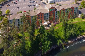 Un hotel Holiday Inn Express con un parcheggio, circondato da alberi e da un fiume.