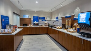 A modern, well-lit breakfast area with wooden cabinets, a coffee machine, and a digital menu board. - Holiday Inn Express Portland SE- Clackamas Area by IHG (Gladstone)
