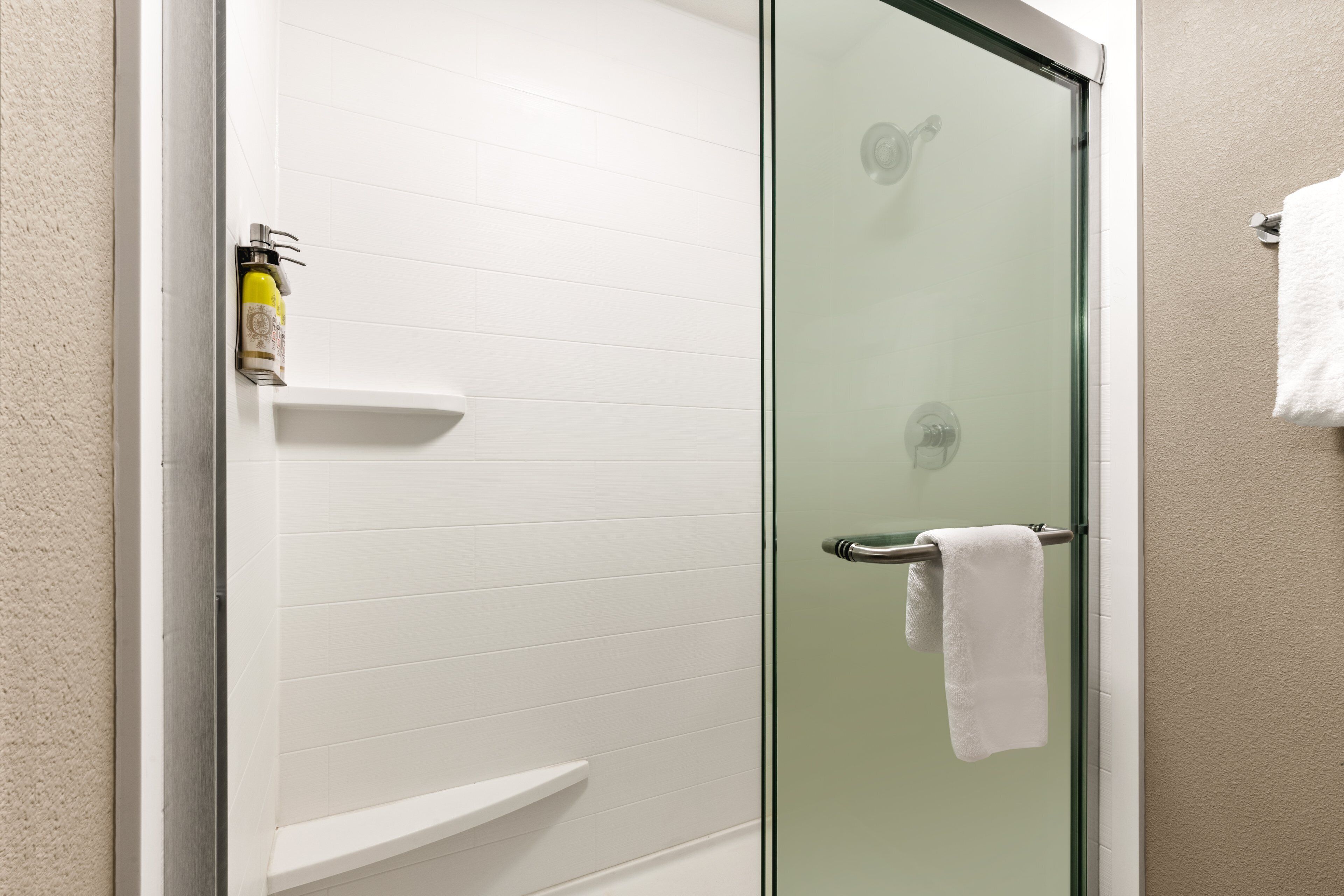 A glass-enclosed shower with a white towel hanging on the door handle.