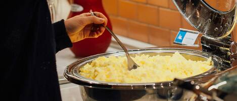 Een buffet met een grote metalen kom vol aardappelpuree.
