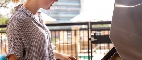 A person grilling outdoors with a modern building in the background.
