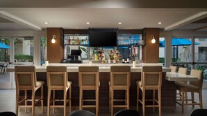 A bar area with wooden chairs and tables, a TV screen, and a variety of bottles and glasses on the shelves. - HYATT house San Diego/Sorrento Mesa (San Diego)