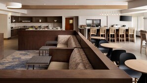 A modern hotel lobby with a long seating area, a kitchen in the background, and a bar area with multiple tables and chairs. - HYATT house San Diego/Sorrento Mesa (San Diego)