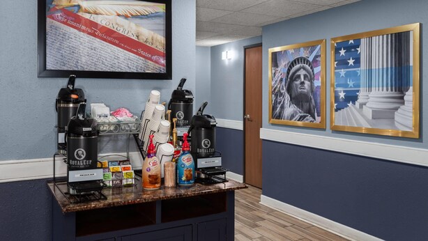A bar area with coffee machines, a coffee dispenser, and a variety of beverages. - AmericInn by Wyndham Austin (Austin)