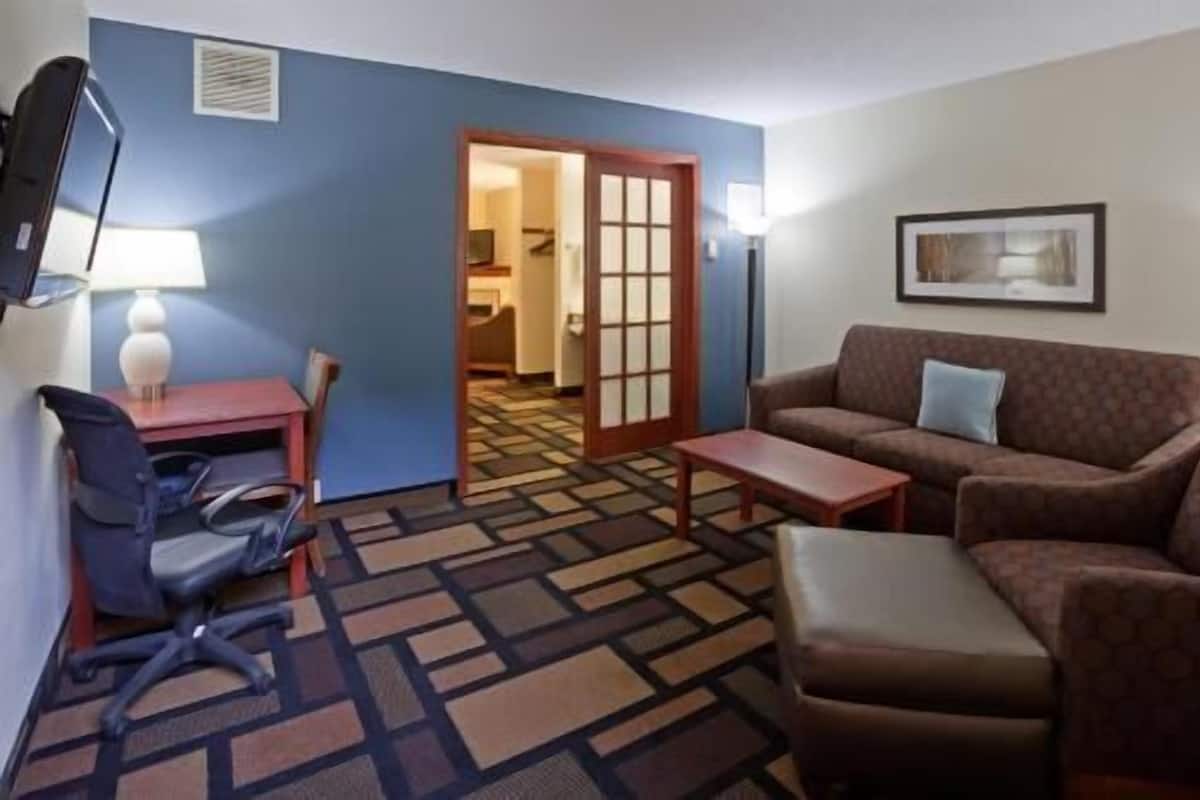 A hotel room with a sofa, armchair, desk, and chair.