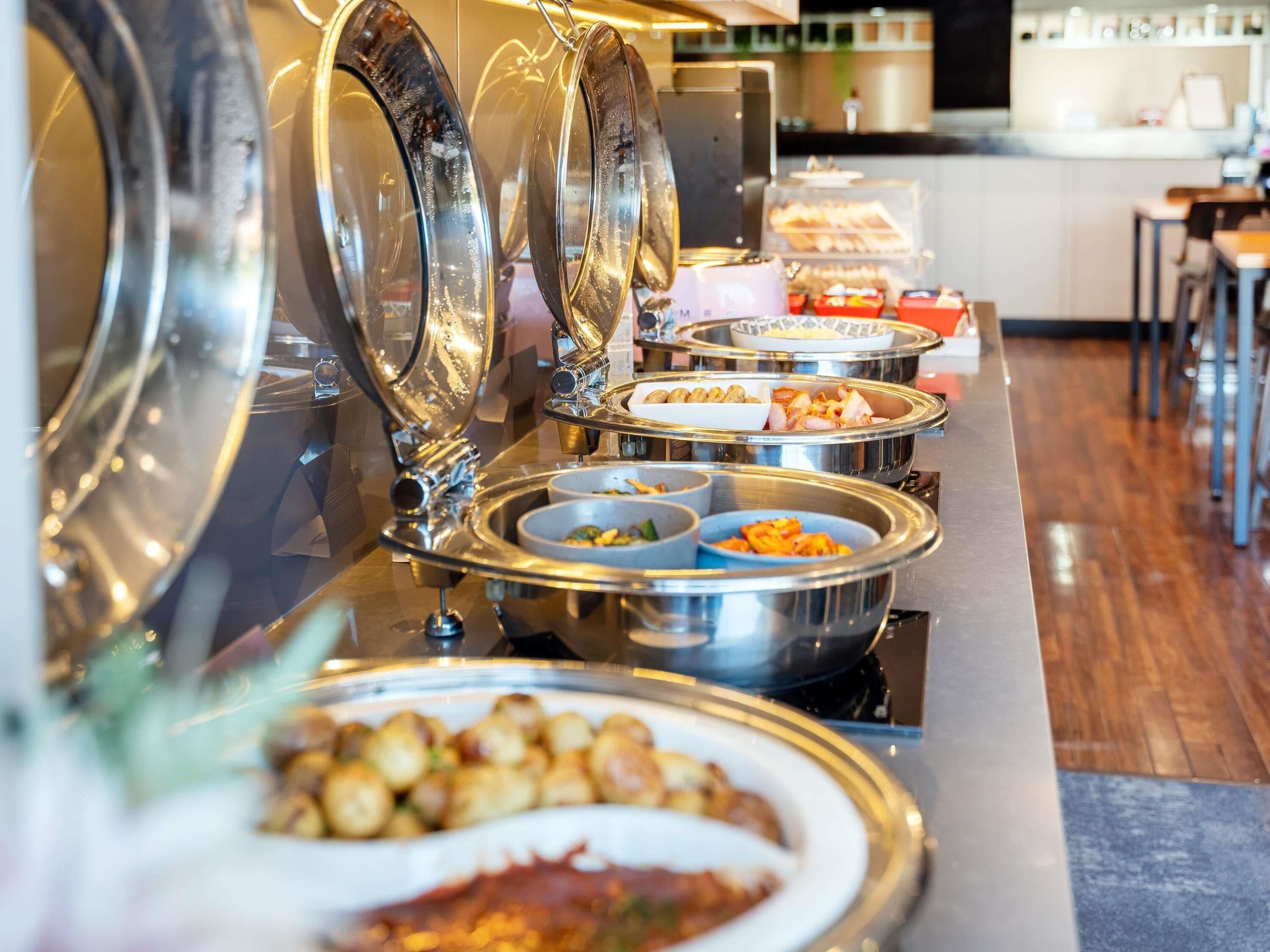 A buffet with various food items in metal serving dishes.