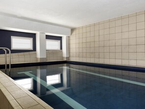 A swimming pool with clear water, tiled walls, and a metal ladder.