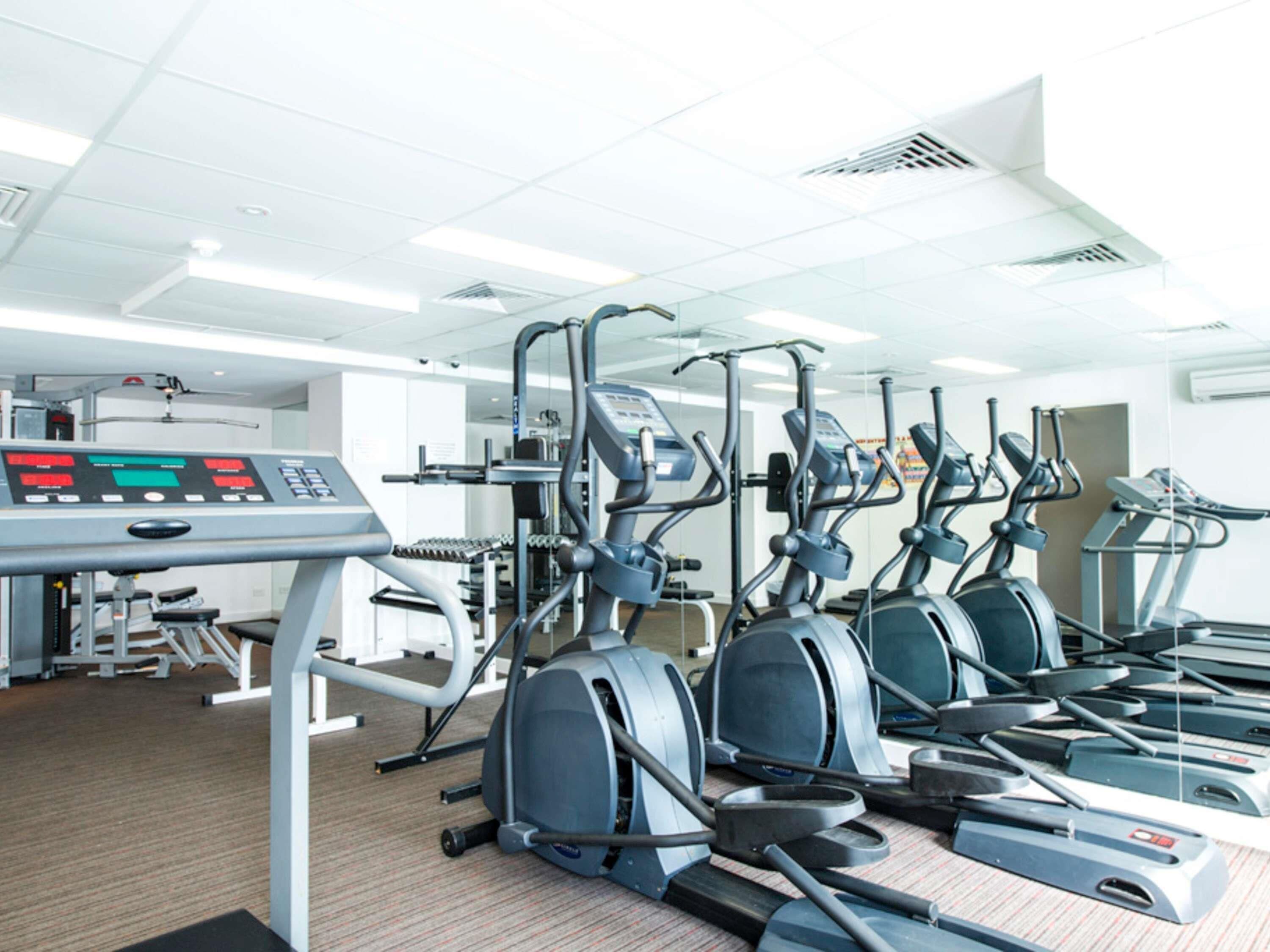 Una palestra con diverse macchine cardio, un pannello di controllo e una panca per pesi.
