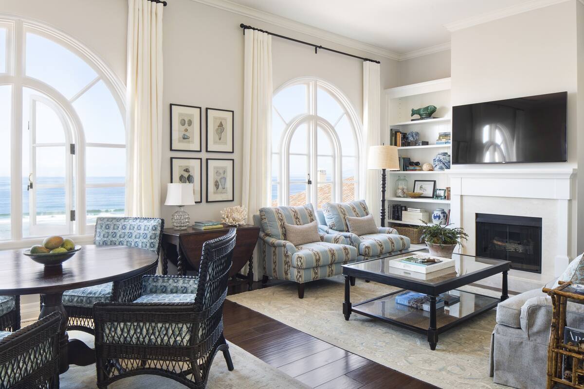 A spacious living room with a fireplace, large windows, and a view of the ocean.