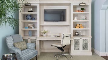A study with a desk, chair, TV, shelves, and decorative items.