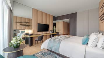 Ein modernes Hotelzimmer mit einem großen Bett, einem Schreibtisch, einem Flachbildfernseher und einer Sitzecke.