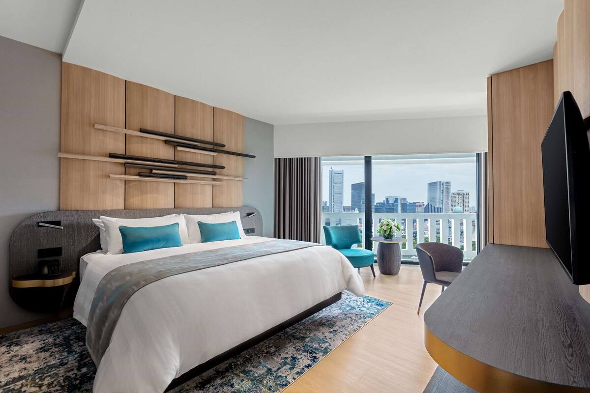 Ein modernes Hotelzimmer mit einem großen Bett, einem Schreibtisch und Blick auf die Stadt.