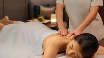 Eine Person erhält eine Massage in einem Zimmer mit Bett, Nachttisch und Lampe.