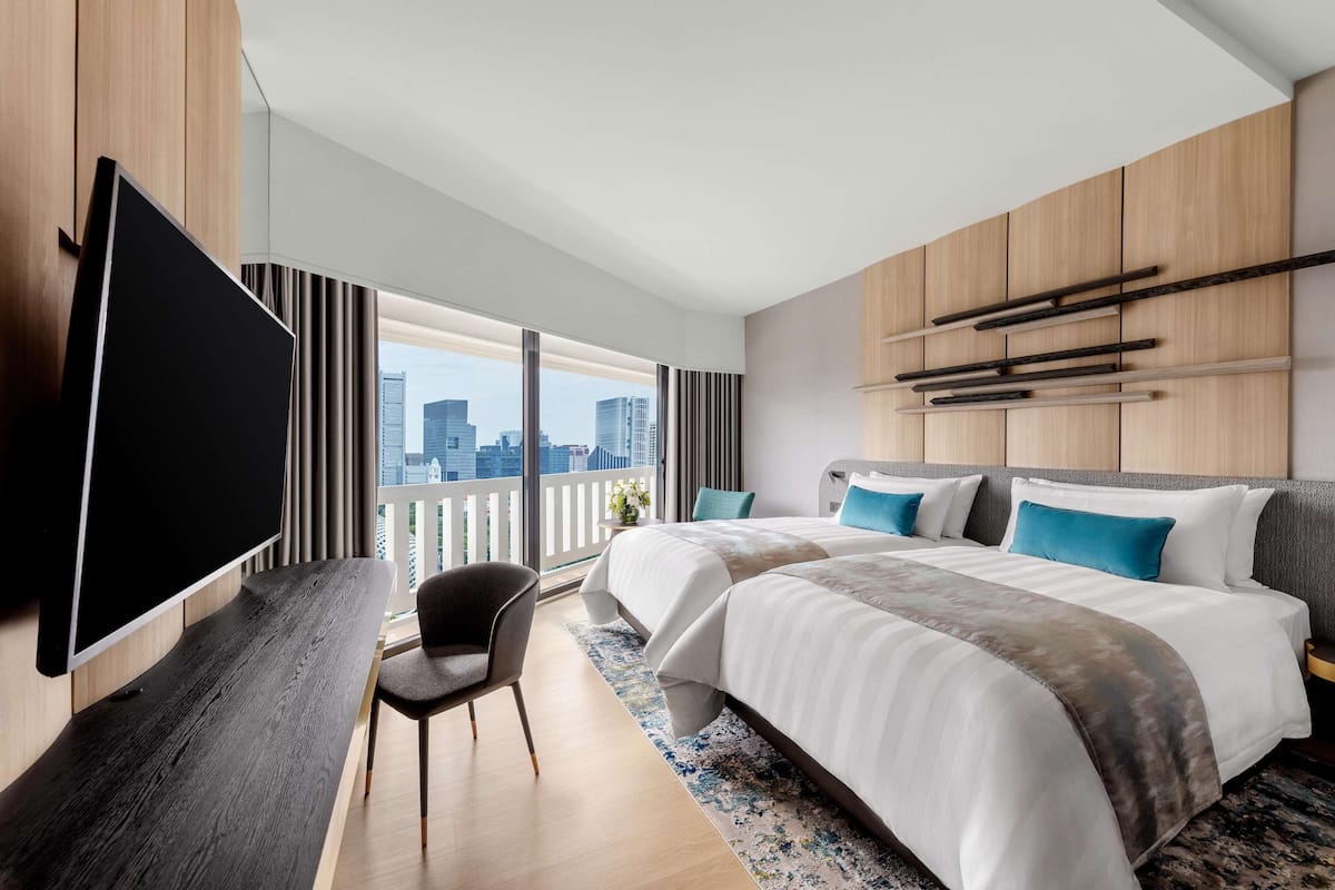 Ein modernes Hotelzimmer mit einem großen Bett, einem Flachbildfernseher, einem Schreibtisch und Blick auf die Stadt.