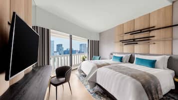 Una habitación de hotel moderna con una cama grande, un televisor de pantalla plana, un escritorio y vistas a la ciudad.