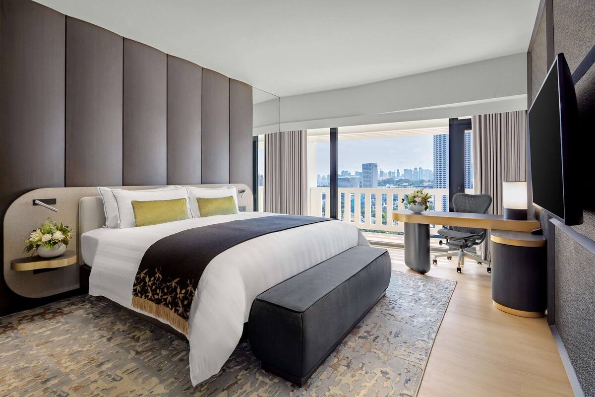 Ein modernes Hotelzimmer mit einem großen Bett, einem Schreibtisch und Blick auf die Stadtlandschaft.