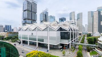 A modern building with a unique geometric roof design, surrounded by high-rise buildings.