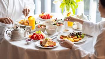 A breakfast table with various dishes, a pitcher, and a vase with flowers.