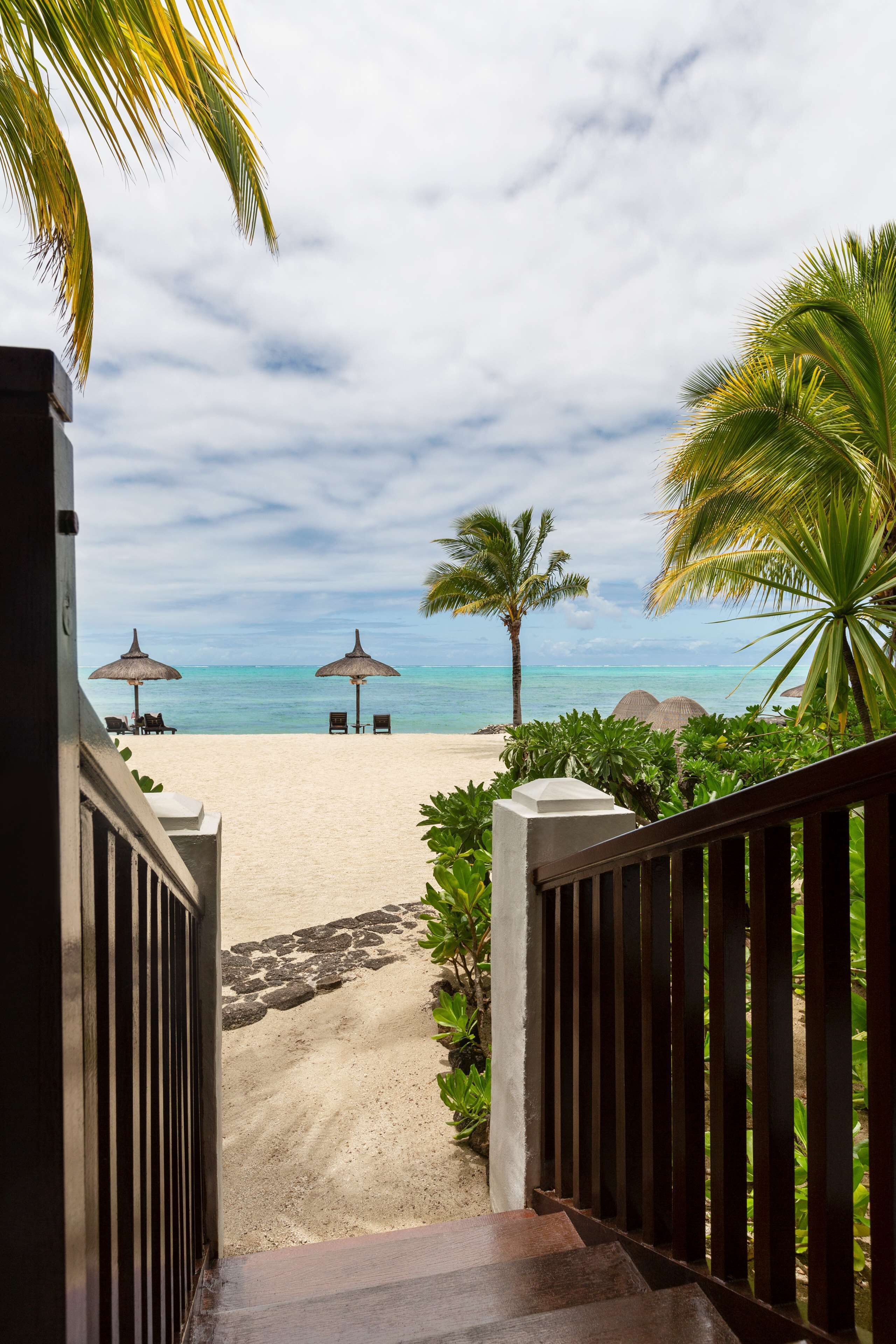 Une vue sur la plage avec un sentier menant à des chaises de plage et des parasols.
