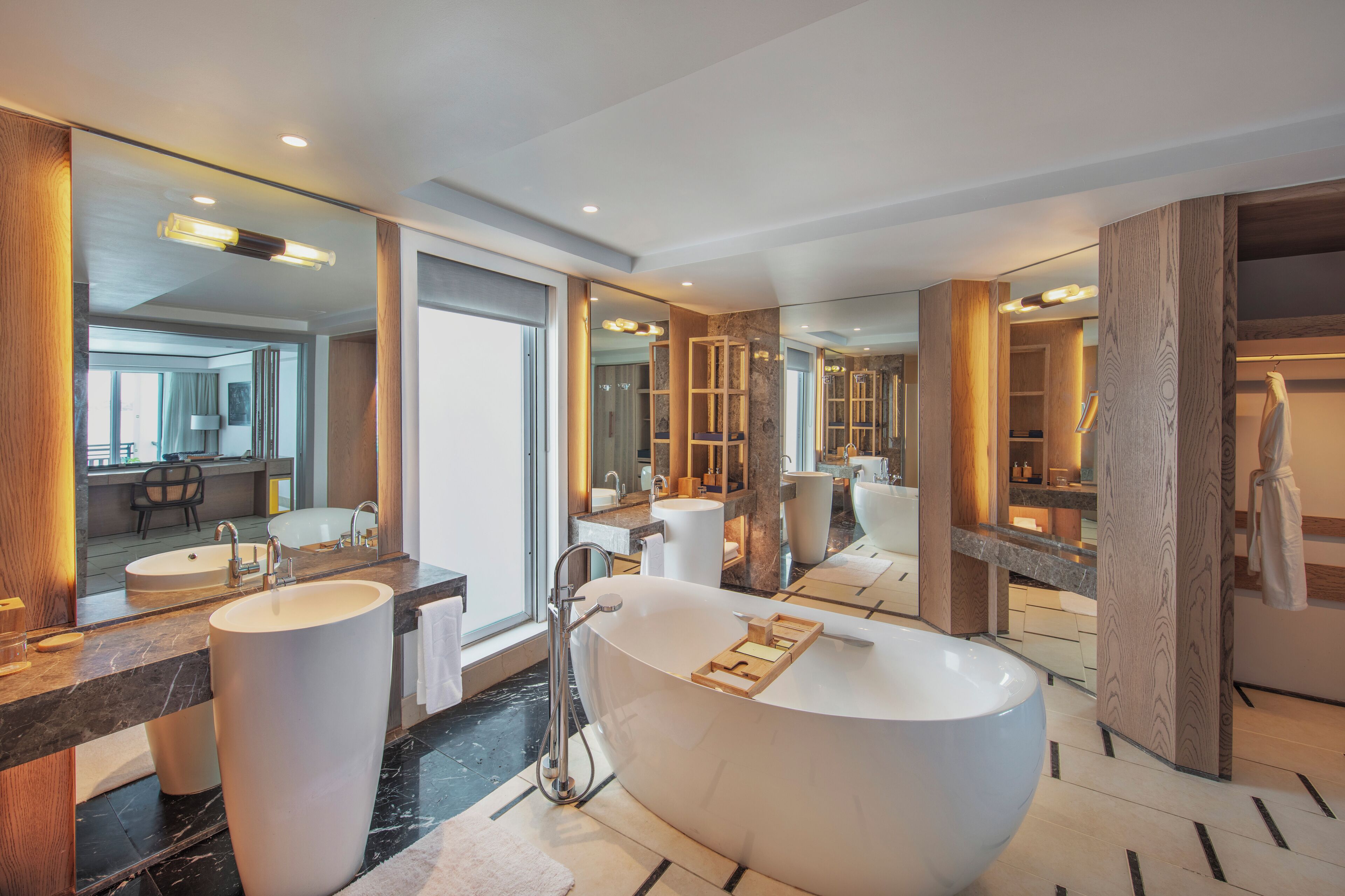 A modern bathroom with a large freestanding bathtub, two sinks, and a large mirror.