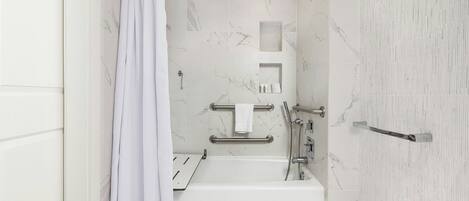 A modern bathroom with a bathtub, shower, and grab bars.