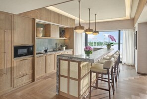 A modern kitchen with wooden cabinets, a built-in microwave, and a marble countertop.