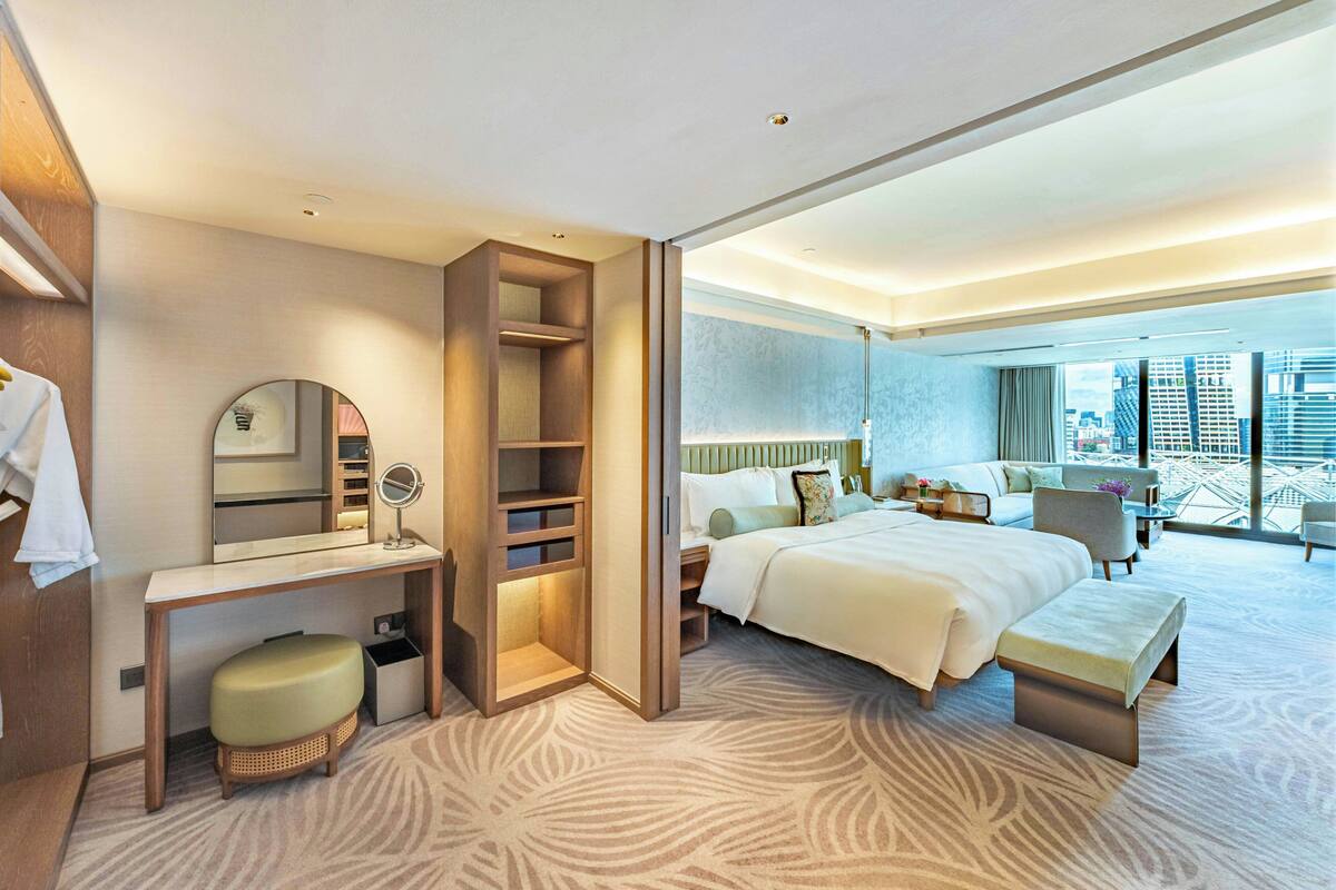 Een moderne hotelkamer met een bed, bureau en zithoek, met uitzicht op de stad.