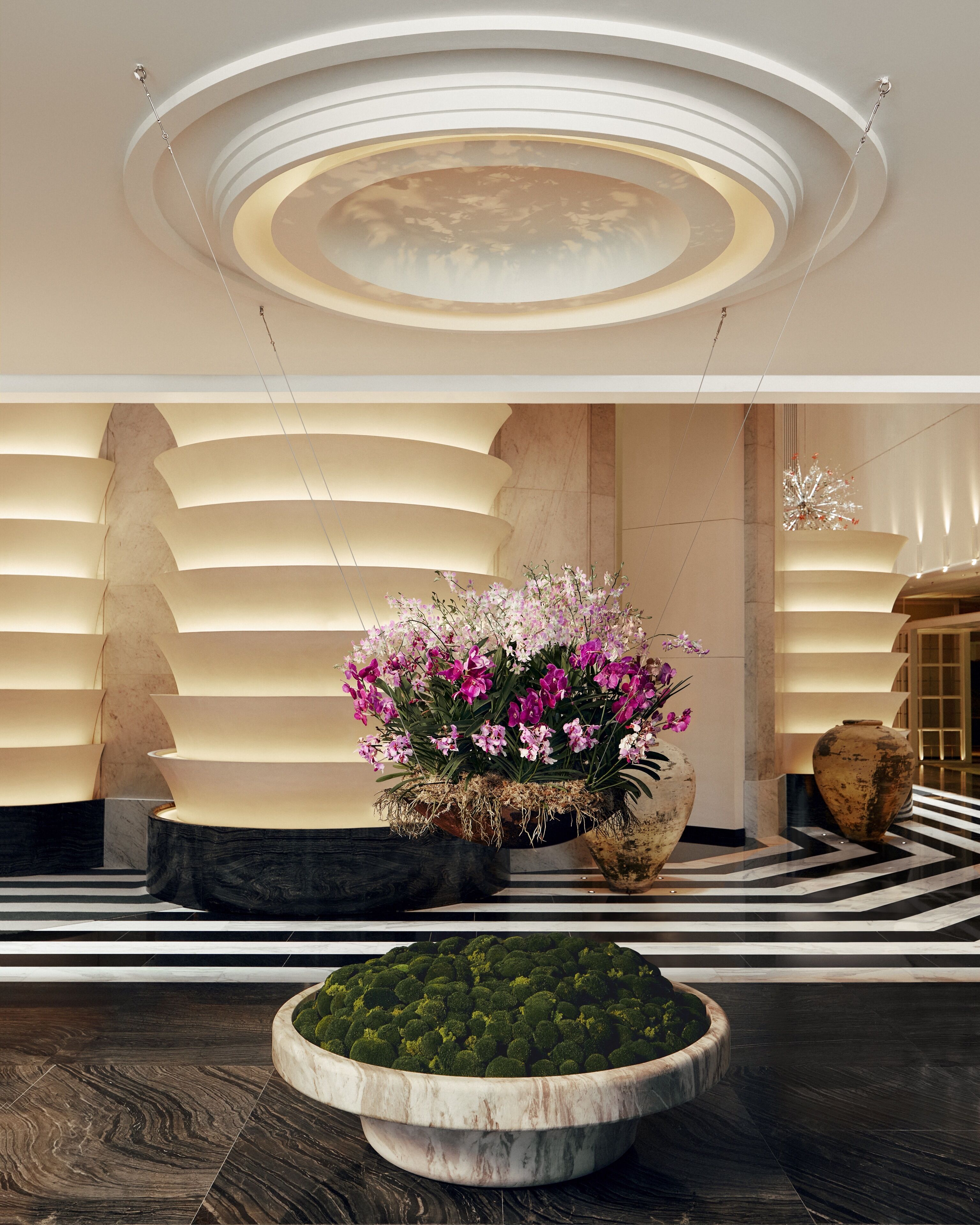 A modern lobby with a central floral arrangement, a patterned floor, and a unique ceiling design.